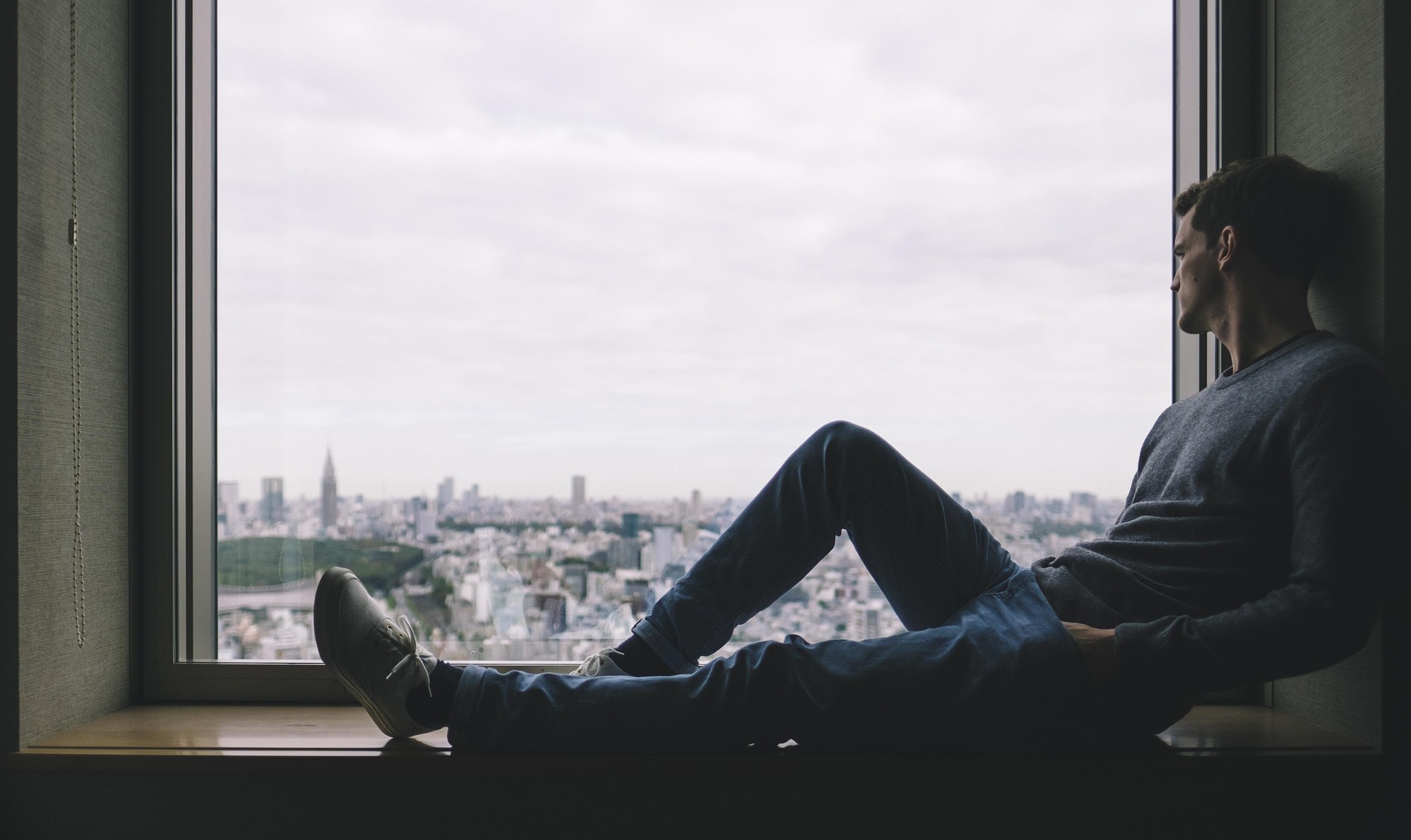 A person sitting quietly near a window, looking outside peacefully, representing calmness during anxiety