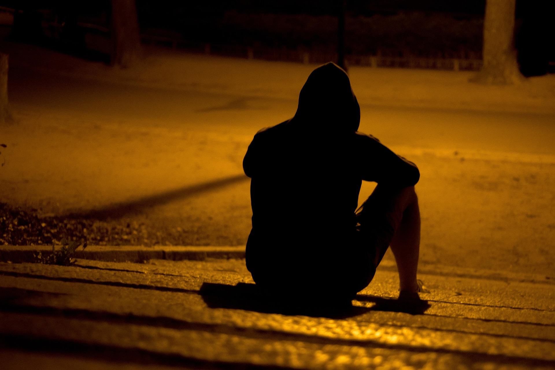 A person sitting quietly with their hand on their chest, eyes closed, in warm dim light — representing the mind-body connection during anxiety