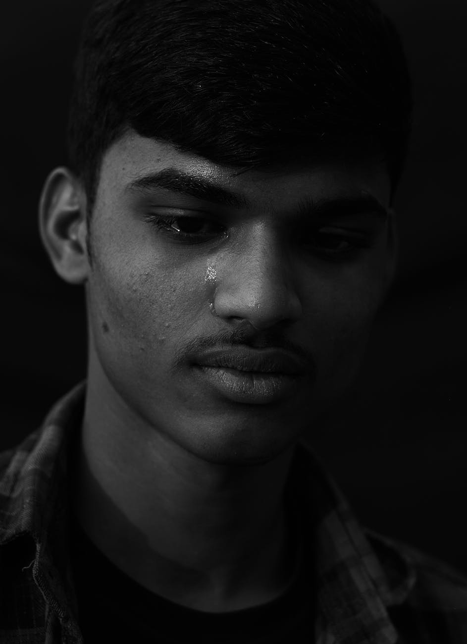 A young man with tears on his face looking distressed — representing health anxiety and emotional struggle