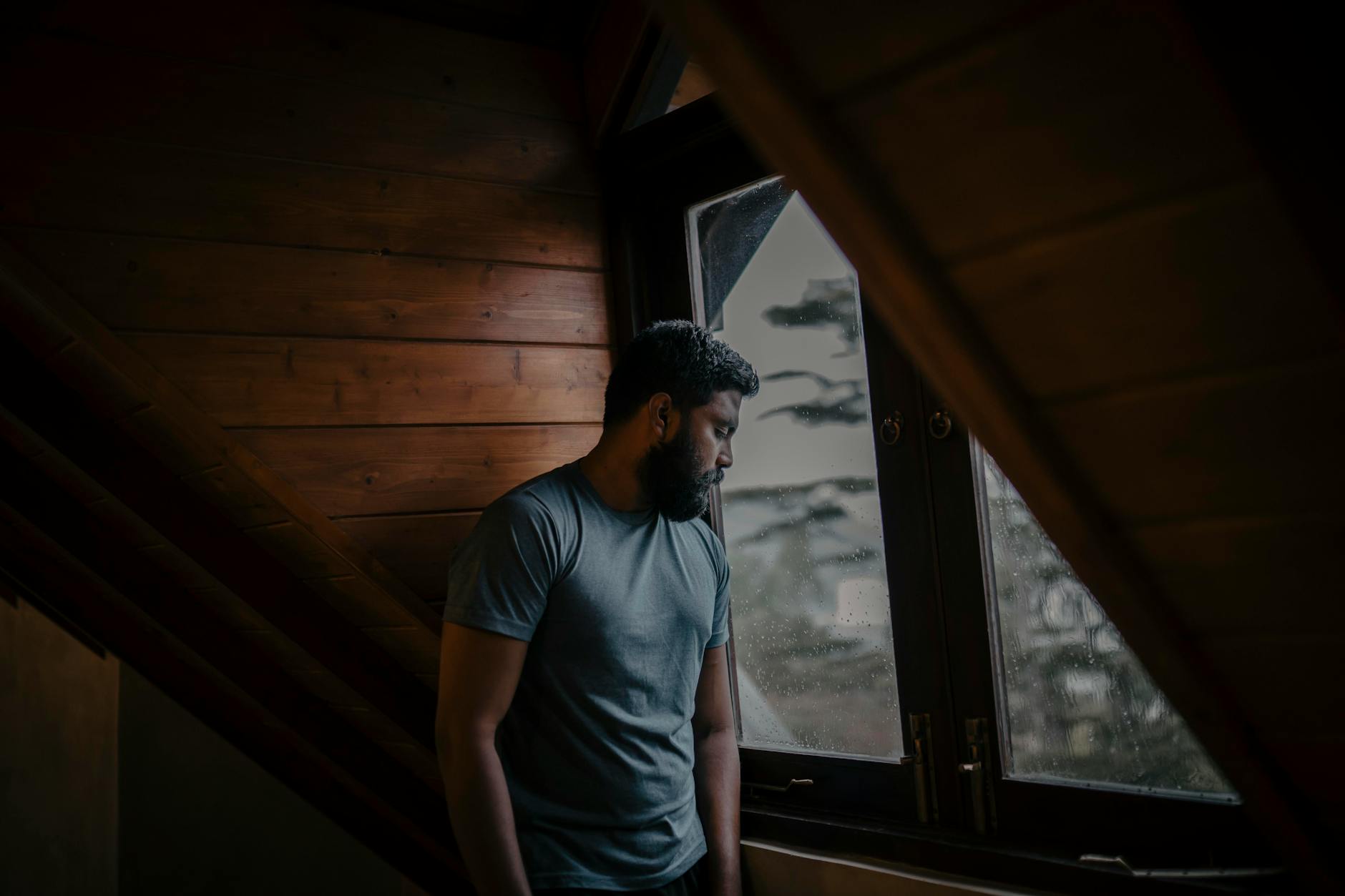 A person standing by a window looking outside, reflecting on anxiety symptoms that felt like a serious illness