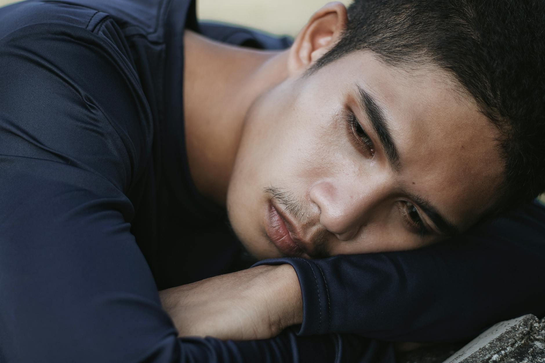 A man lying down looking exhausted and overwhelmed, representing anxiety and mental fatigue